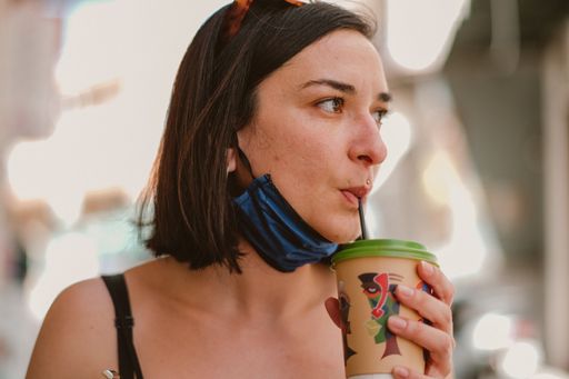 A shallow focus of a woman drinking takeaway coffee using a straw