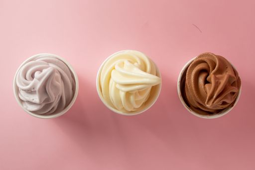 A top view of chocolate, vanilla, and taro soft serve ice cream on a pink table