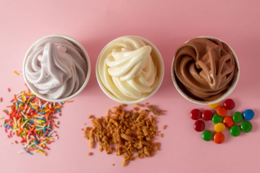 A top view of chocolate, vanilla, and taro soft serve ice cream on a pink table