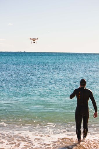 A vertical shot of a man swimming in the sea on a sunny day