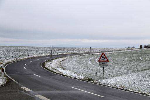 An empty road in a snowy area under a cloudy sky