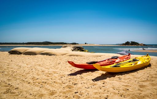 Two surf skis on the sandy beach with the sea in the background under a clear blu sky