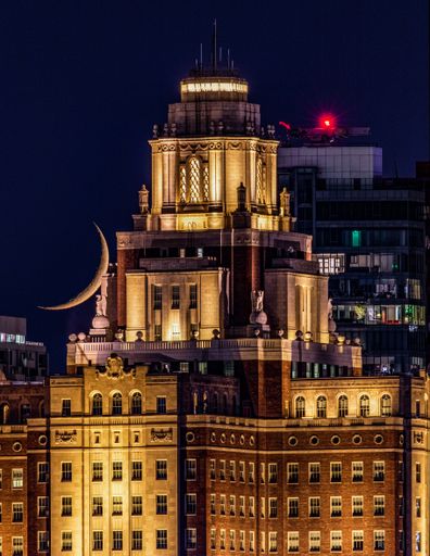 A vertical shot of a building in Philadelphia during moon set