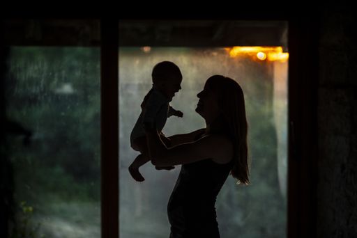A silhouette of a mother holding her daughter in her arms inside their home