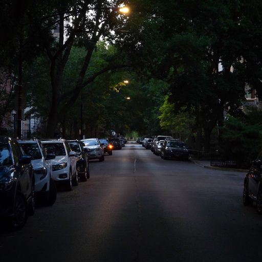A small street in Chicago illuminated with street lights and with cars parked on the sides
