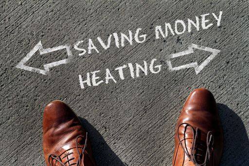 Person having to decide between Heating and Saving Money - top view of the words and arrows pointing in opposite directions