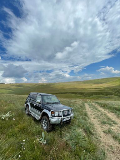 A vertical shot of an off-road car in the mountains for an adventure road trip