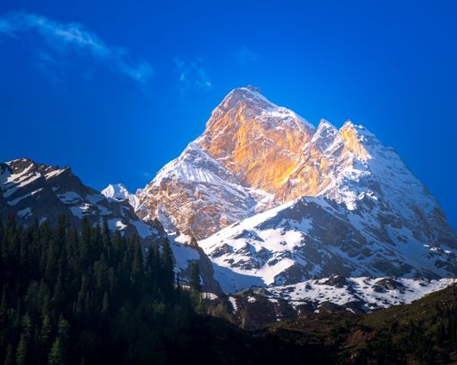 A beautiful view of a golden mountain covered in snow under a blue sky.