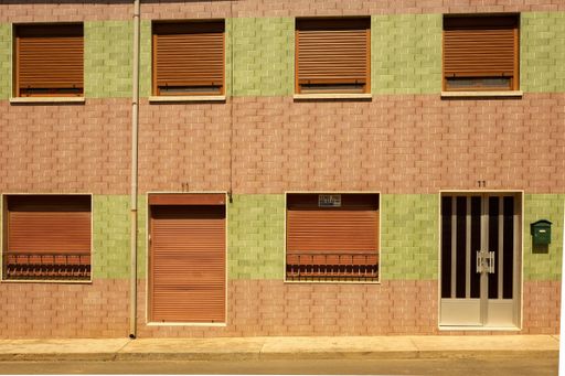 A brick wall of a building with blinds on the windows