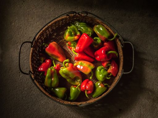A top view of a basket with green and red peppers