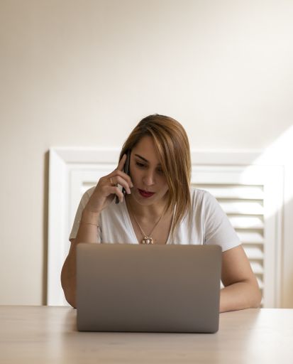 A young female talking on phone while working on laptop