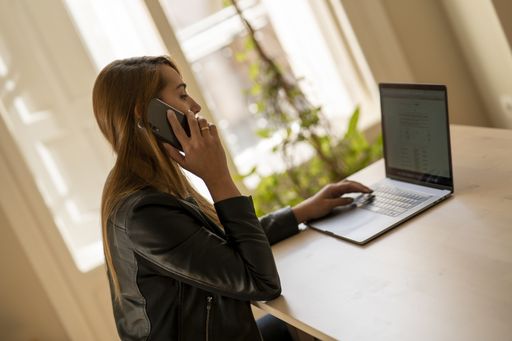 A young female talking on phone while working on laptop