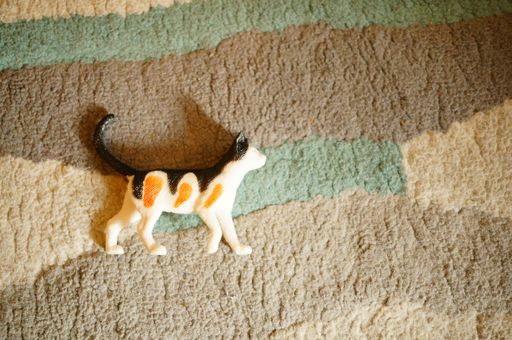A flat lay of a plastic toy cat on a rug