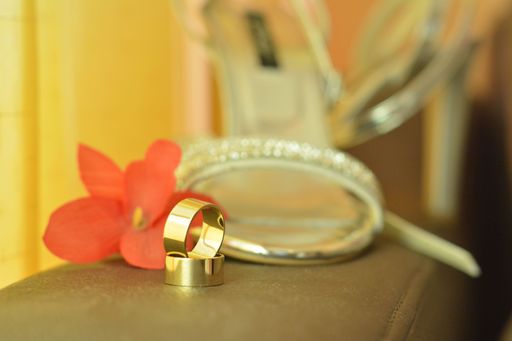 A closeup shot of a pair of golden wedding rings with blurred shoes on the background