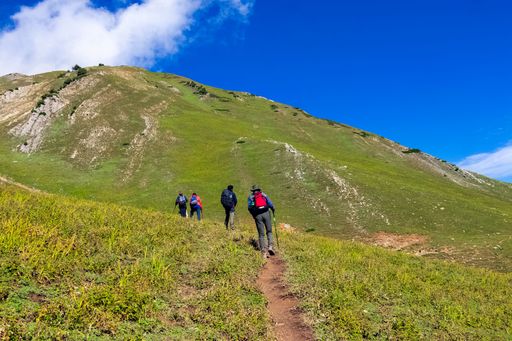 A closeup shot of hikers climbing up a mountain under the blue sky on a sunny day