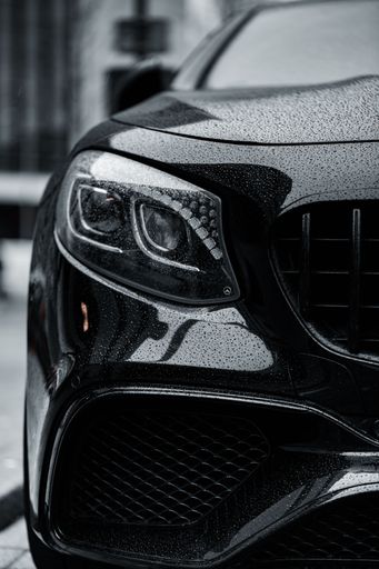 A vertical greyscale shot of a black car front