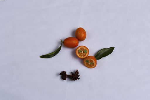 A top view of a cut and whole kumquat on a white background