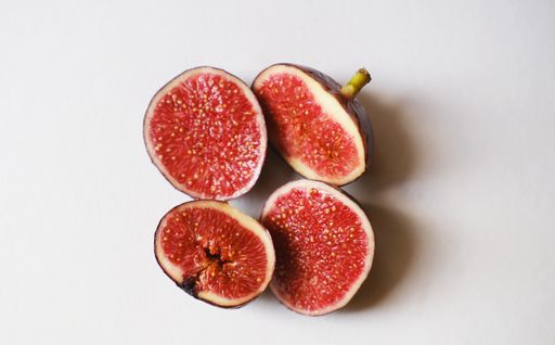 A closeup of cut figs on a white surface under the lights