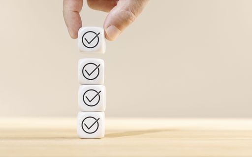 Hand holding a cube block on top of other blocks stacked with check icon. Checking or checklist concept. Copy space