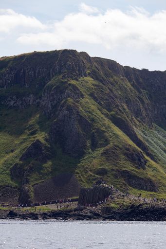 A vertical shot of Giant's Causeway mountains in cloudy sky background in a rural area