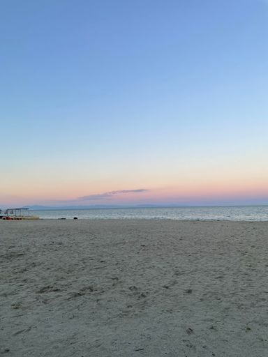 A vertical shot of a scenic beach with a sunset skyscape in the background
