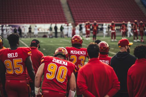 The group of Football players in red uniforms looking towards the football field