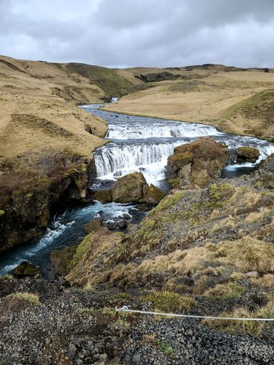 A vertical shot of a river flowing in the wilderness in Iceland on a cloudy day