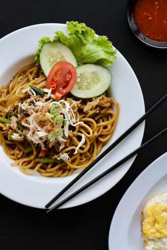 A vertical shot of tasty pasta with cucumber and tomato served in a white plate on a table