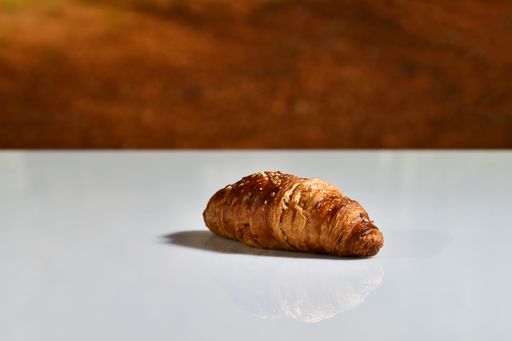 Close up of a delicious looking homemade croissant on a table on an out of focus background. Traditional food and breakfast concept.