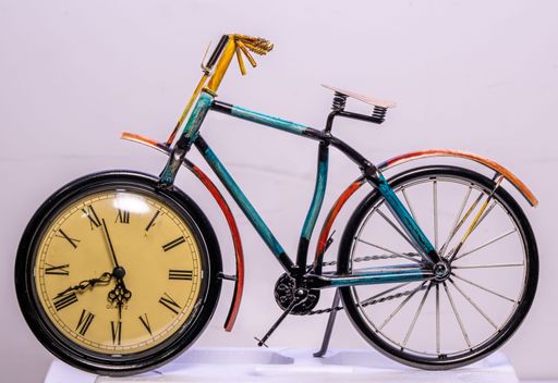 A closeup shot of a vintage bicycle clock standing next to wall