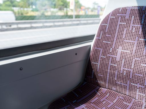 An empty seat by the window inside a public passenger bus