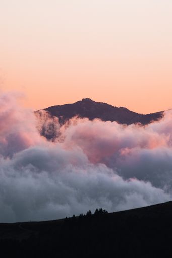A vertical shot of hill silhouettes covered in the fog - perfect for wallpapers