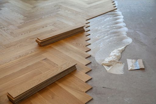 A worker laying parquet flooring and installing wooden laminate