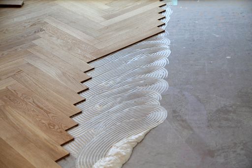 A worker laying parquet flooring and installing wooden laminate