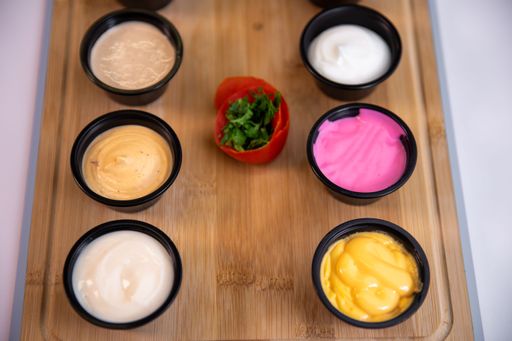 A closeup shot of different sauces in small bowls on a wooden board