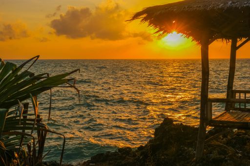 A view of a small hut near the ocean during sunset