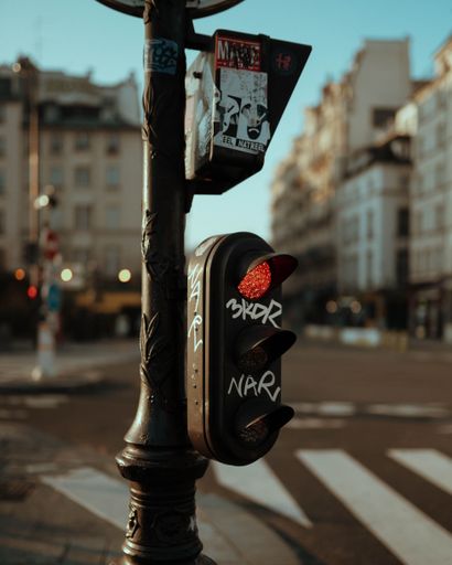 A closeup view of a traffic light showing a red light in the city center of Paris