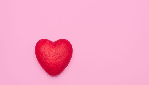 A red heart against pink wall