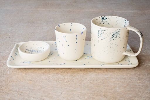 Different sizes of luxury white ceramic dipped mugs on white tray on marble background