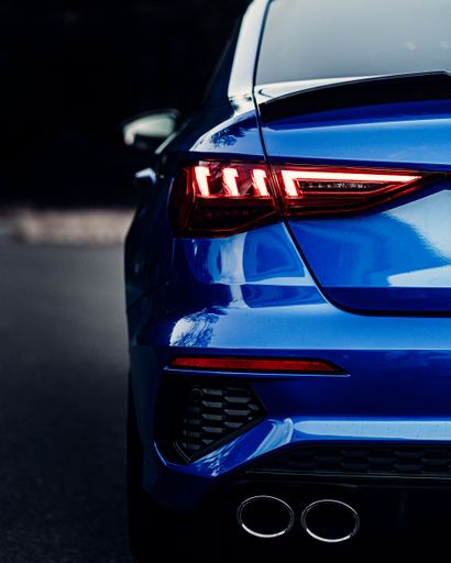 A back view of a shiny blue sport car lights with blur background, vertical shot