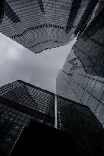 A vertical low-angle shot of tall office buildings against the cloudy sky