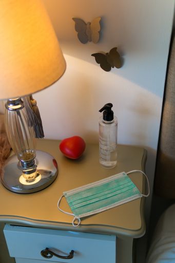 A vertical shot of a lampshade and medical mask on a bedroom shelf - new normal