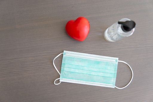 A high angle shot of a medical mask and hand sanitizer on a wooden surface - new normal