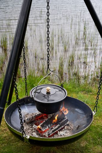 The best way to cook on an open fire with camp oven tripod. Picnic in nature near lake