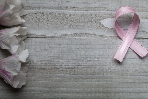 A flat lay of a wooden surface with ribbon and flowers on the sides - free space for text