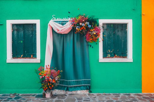 A colorful house facade with curtained doorway beautifully decorated with fresh colorful flower bunches
