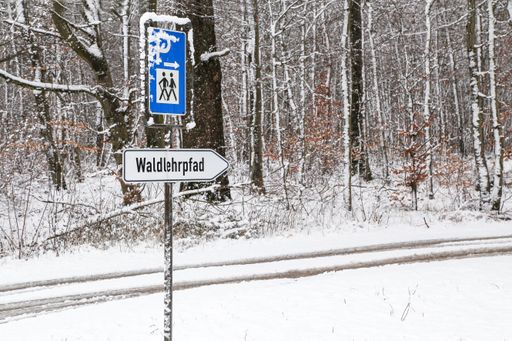 A german sign indicating the hiking trails on snowy weather during daylight