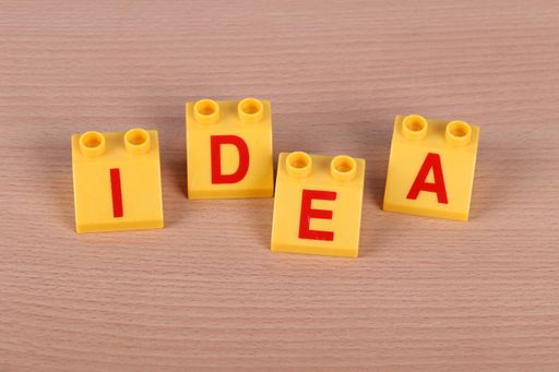a top view of the word IDEA laid out by yellow lego bricks on a brown background