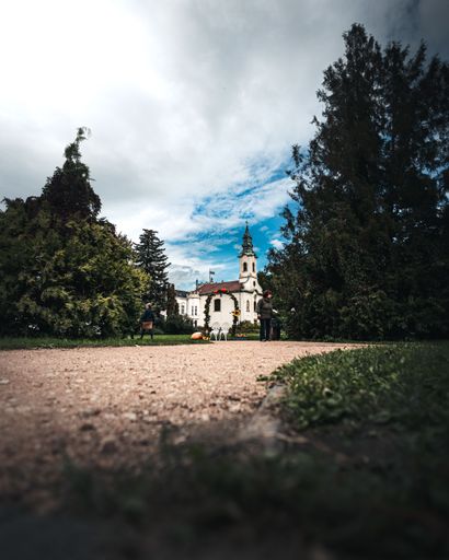 A vertical shot of an unpaved path through a park leading to a beautiful white castle