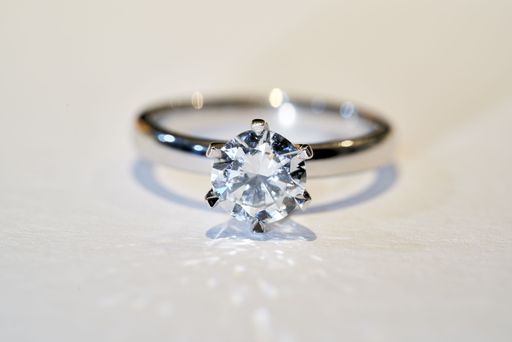 A closeup of a beautiful white gold wedding ring set with a diamond under bright artificial lighting